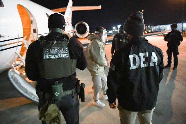 U.S. Marshals Fugitive Task Force Deputy and DEA special agent standing in front of plane on arrival of U.S. fugitive.