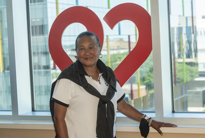 Paula stands at the window posing with a heart behind her.