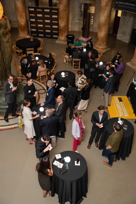 An aerial view of dozens of people mingling around tables. 