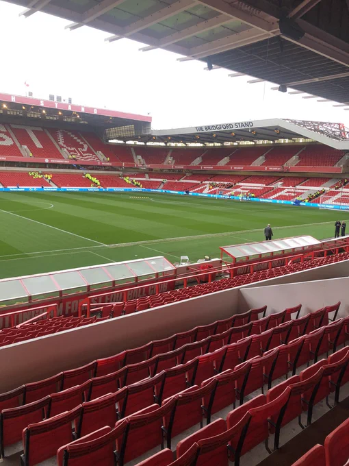 Photo taken from the Pater Taylor/Main Stand at Nottingham Forest’s City Ground. Looking diagonally left to where the Brain Clough and Bridgford Stands meet. The ground is empty in the daylight and the green playing surface can be seen in between the relevant stands.