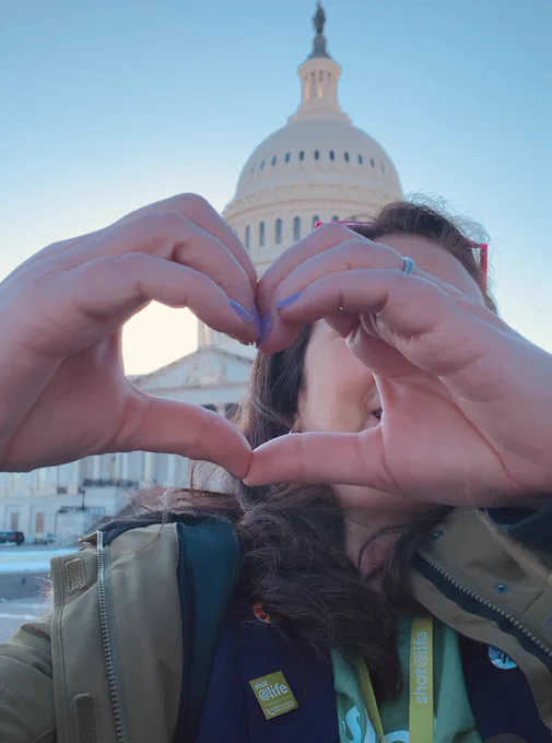 Woman holding hands in a heart shape in front of US Capitol building