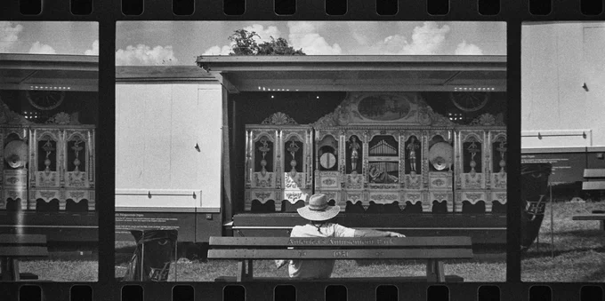 Appalachian Fair, Gray, Tn.  A man in a hat sits idly before an old attraction as the sun grazes him with delicate specificity.