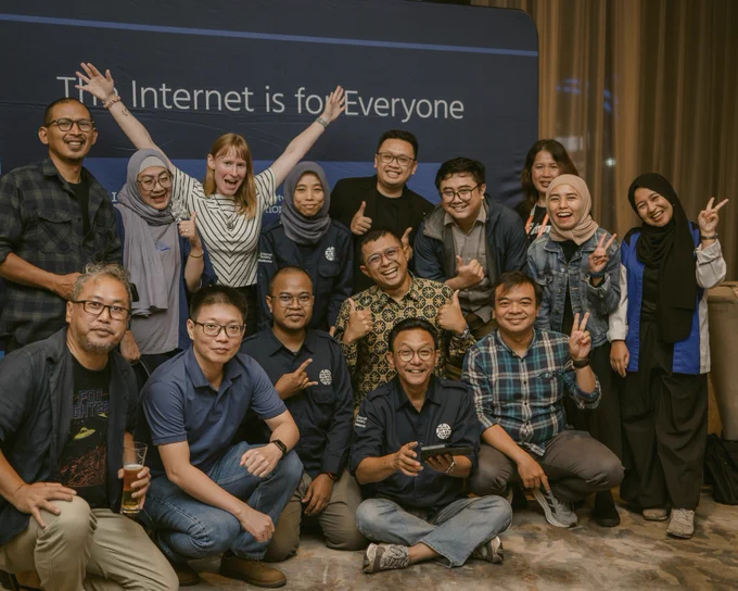 A group of people smile and post in front of an Internet Society sign
