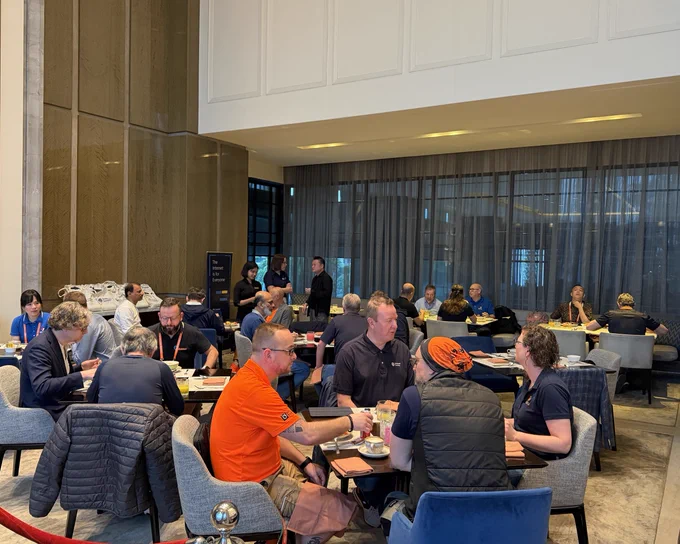 A group of people sit at tables and eat breakfast