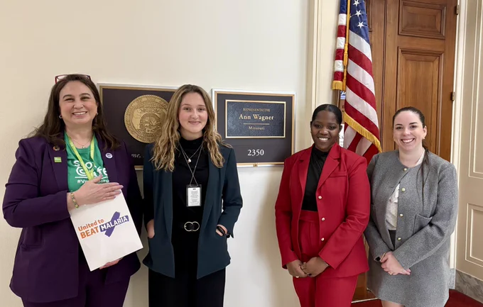 Four people standing by a flag in front of Rep Ann Wagner’s office