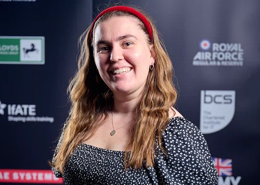 Photo of Phoebe at awards presentation in front of sponsor logoa.