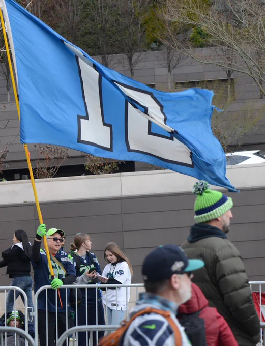 A Seahawks fan waves a giant 12 flag, a flag that represents the Seattle Seahawks fan base.