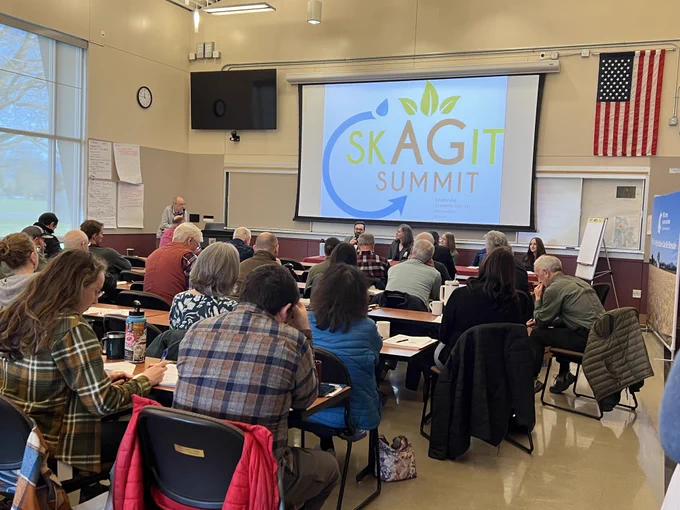 Audience seated in a classroom watching a panel discussion at the Skagit Summit.