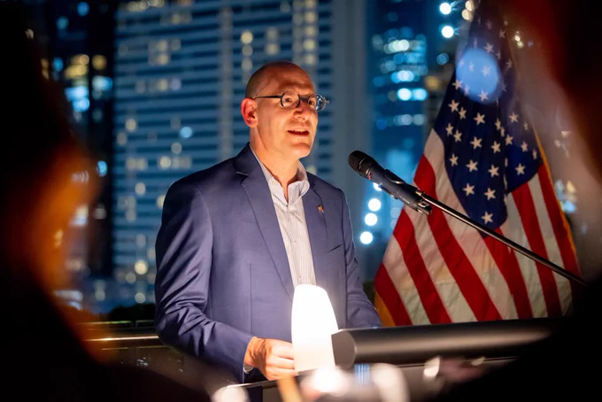 U.S. Embassy Chargé d'Affaires a.i. Robert Ewing speaking from behind a podium.