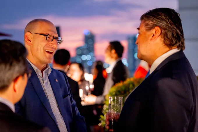Chargé d'Affaires a.i. Robert Ewing and a reception guest conversing.