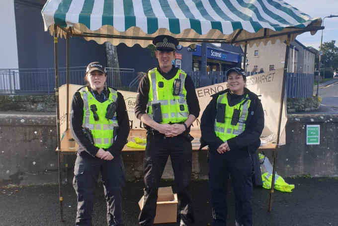 Three officers in full uniform in front of a bike marking stall