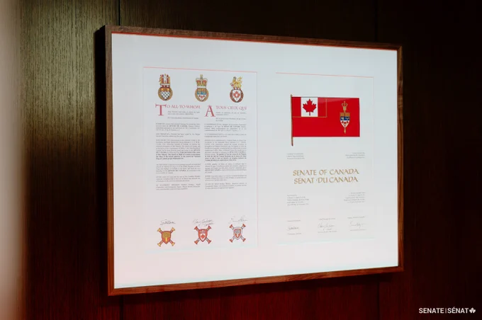 La copie originale des lettres patentes du drapeau du Sénat du Canada, encadré et accroché sur un panneau mural en bois.