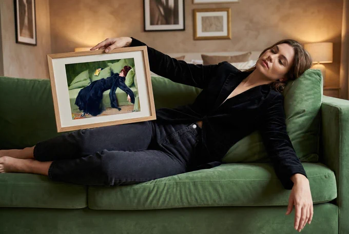 Woman lying on a sofa holding a framed Decadent Young Woman Printable Artwork.