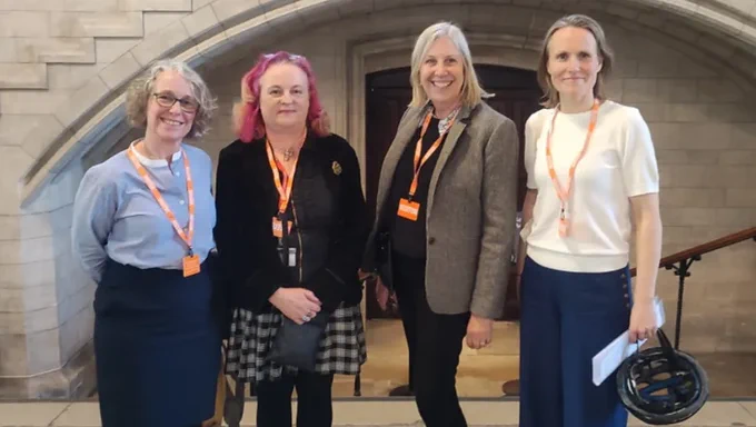 Four women stand smiling in the Houses of Parliament, ready to present their research to Wes Streeting