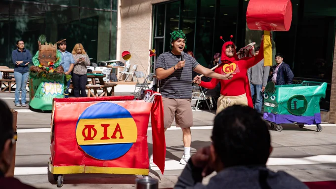 Two TAMIU students dressed as El Chapulín Colorado and Chavo del Ocho with their decorated cart.