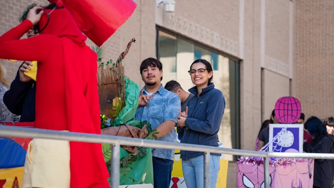 Two students smiling as they push their decorated cart.