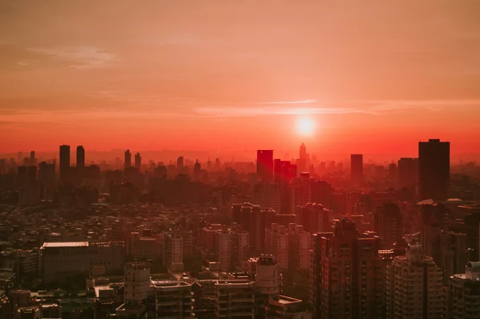 The sun rising above a cityscape with high-rise buildings