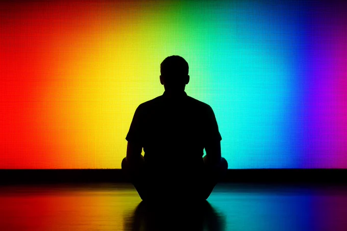 Let us luxuriate here in front of a big 10-bit color gradient! Man sitting silhouetted in front of image.