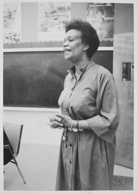 Black-and-white photo of a Black woman standing at the front of a classroom.