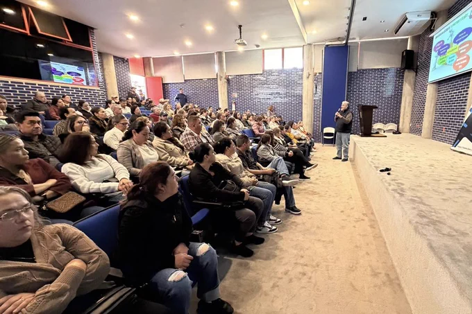 A man stands and speaks to a seated audience at a Mexico Chapter cybersecurity training.