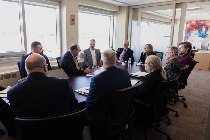 A group of ten people in business attire sit around a conference table in a modern office, engaged in a meeting. Sunlight streams through large windows, and colorful art hangs on the wall in the background.
--
Dans un bureau moderne, un groupe de dix personnes en tenue de travail est assis autour d'une table de conférence et participe à une réunion. La lumière du soleil traverse de grandes fenêtres et des œuvres d'art colorées sont accrochées au mur à l'arrière-plan.