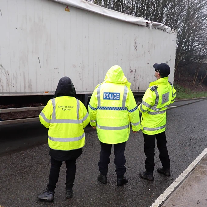 Officers from the Environment Agency, police and DVSA are shown next to a lorry trailer on a roadside. 