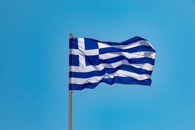 The flag of Greece flying in the wind against a blue sky background. 