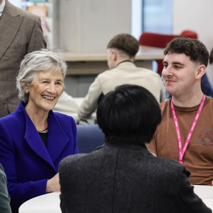 President of Ireland Catherine Connolly engaged in a focused discussion around a white table in a modern office setting.