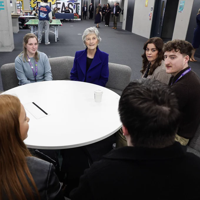 President of Ireland Catherine Connolly seated around a round white table with students 