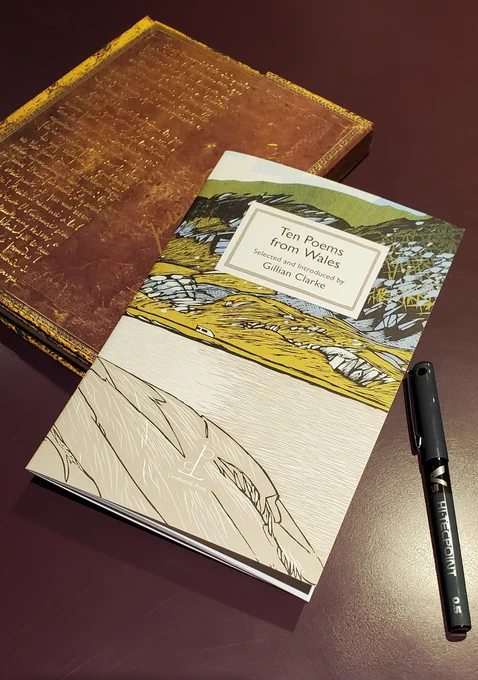 Poetry chapbook Ten Poems from Wales (Candlestick Press) sits with a notebook with an ornate gold cover and a black pen