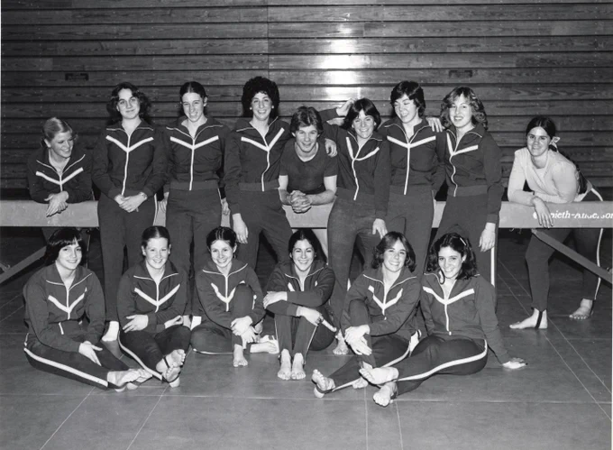 The UVM women's gymnastics team in 1981 poses for a photo next to a balance beam.