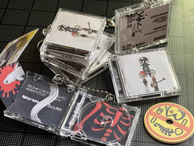 A number of miniature CD cases for the band Diss-Pair with keychains attached. Once is open showing the insert, next to a mini CD
