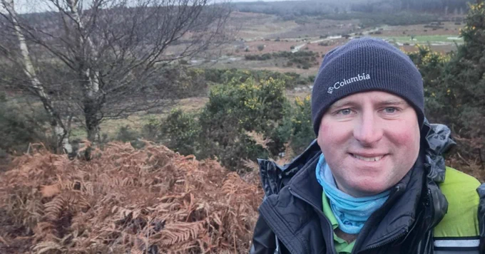 New Forest NPA ranger takes a selfie with a heathland landscape behind him.