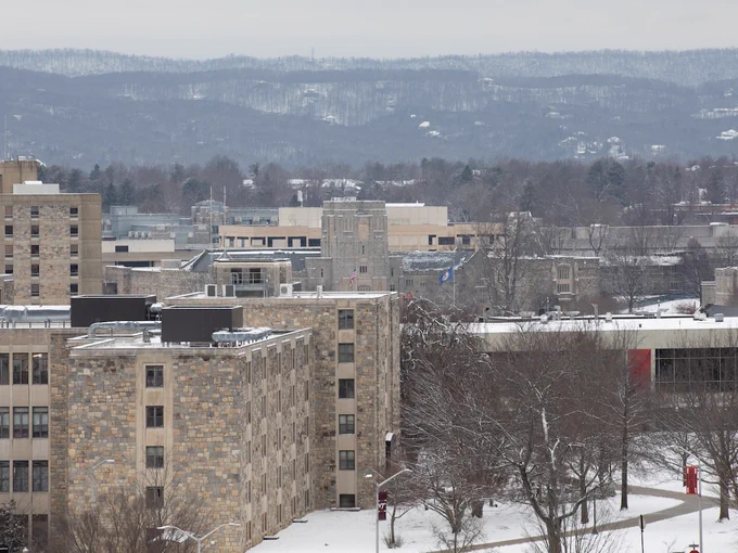 Blacksburg campus on a snowy afternoon featuring grey Hokie Stone buildings and pedestrian pathways. 