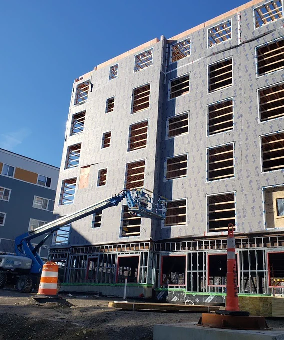 A photo of the Amory Street development, a multi-story building under construction with exposed window frames and a blue sky background.