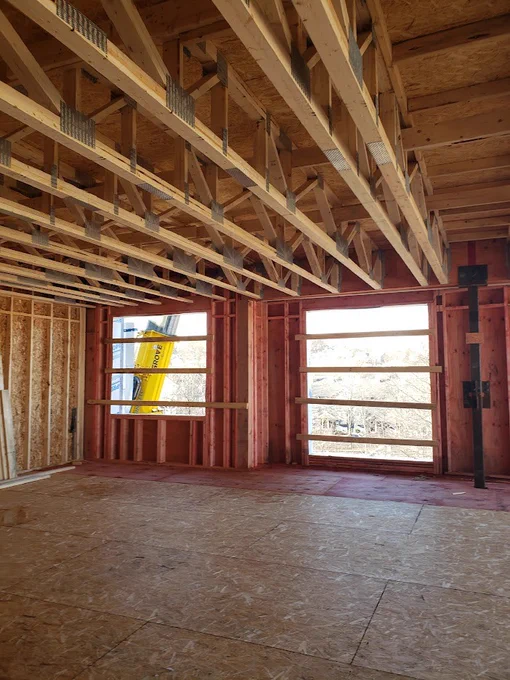 Photo of the interior of Amory Street with wooden-framing under construction with exposed ceiling joists and large window openings.