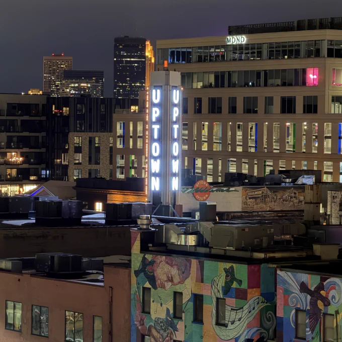 Downtown Minneapolis skyline at night with Uptown theater sign in the foreground