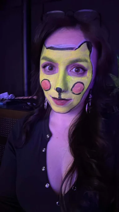 Steph has a painted yellow face with red circles on her cheeks to resemble the Pokémon pikachu, except it looks a little bit cursed.