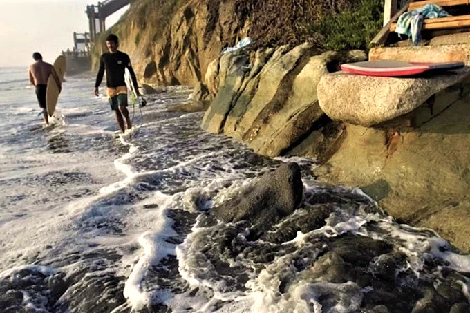 Surfers at the bottom of the trail where it meets the sea