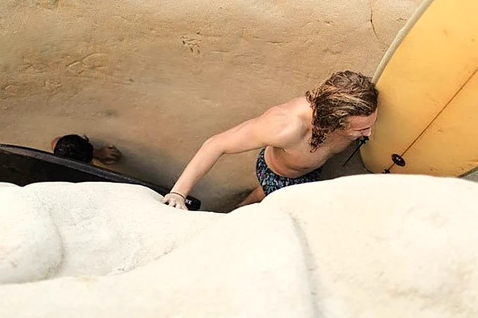 A surfer with his stick squeezing through a narrow section of the trail