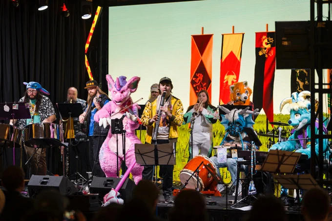 A band of furries playing on a stage! 