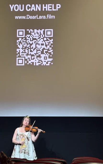 Violinist Lara St. John, wearing a tunic that shows her breaking the columns of classical music's temple, plays her arrangement of "Death and the Maiden" under an onscreen QR code with the heading, "You can help."