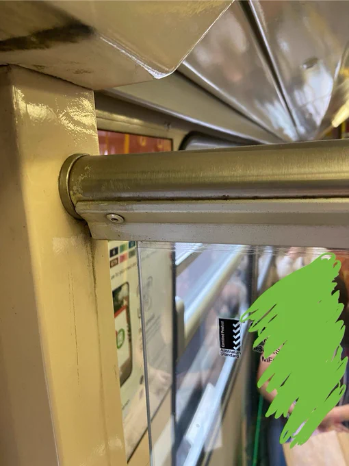 A photo of the panel where it connects to the wall, showing that the glass is quite far away from the wall, maybe 2-3cm? Tram signage, the window and a passenger are visible through the panel.