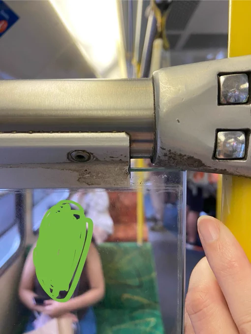 A close up of my hand holding onto the pole of the tram, showing the glass panel much closer to the pole than it should be. The rest of the tram is visible through the panel.