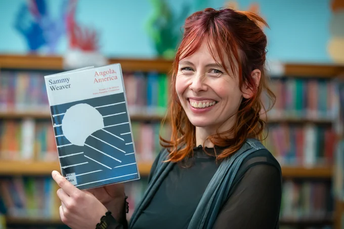 Woman holding a book, smiling 