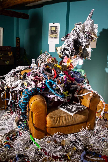Chair covered in twisted bound forms, surrounded by shredded forms teabags and empty tea mug, the forms climb out of the chair and spiral out and around the chair