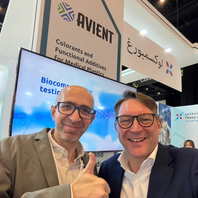 Two individuals standing in front of an Avient booth at a tradeshow