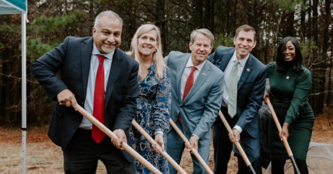A group of people in formal attire are standing together outdoors, holding shovels at Rowen's groundbreaking ceremony.