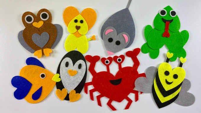 DIY felt animal projects arranged in two rows. Each animal—an owl, dog, mouse, frog, fish, penguin, crab, and bee—is assembled using cut-out felt hearts to create faces, wings, fins, and feet. The bright colors stand out against a clean white surface.
