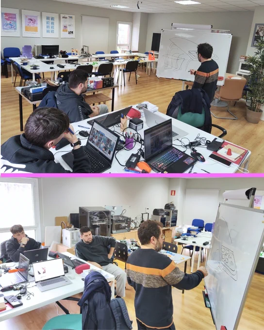 Un empleado de 3DLAN explica un diseño en una pizarra mientras dos estudiantes observan y trabajan con portátiles en el aula-taller.